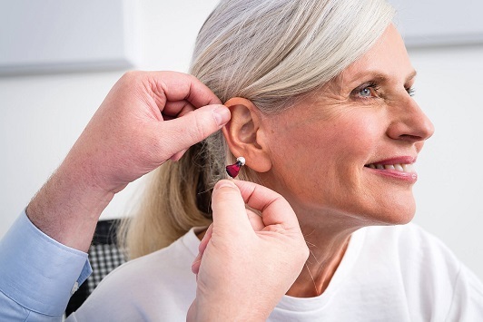 Ältere Frau erhält ein modernes Hörgerät zur Hörverbesserung beim Hörakustiker.